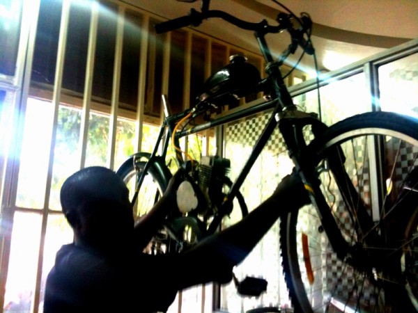 Julius holding up an Adtec motorized bicycle in his shop in downtown Nairobi